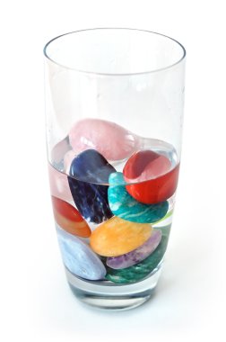 Crystals in half filled glass of water, on white clipart