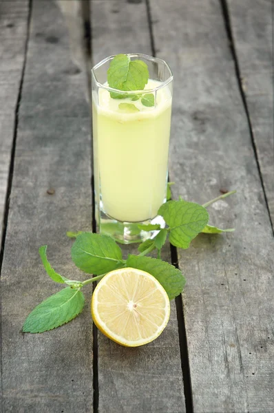 Lemonade with mint and cut lemon on wooden background