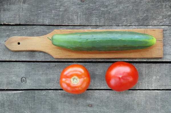 Timun pada pemotongan papan dengan dua tomat — Stok Foto