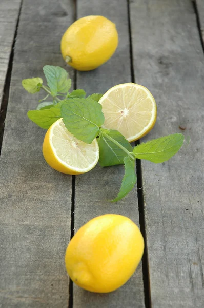 Hele en gesneden citroen met munt op grijze houten achtergrond — Stockfoto