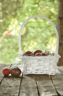 eski ahşap masa üzerinde beyaz sepet içinde Paskalya yumurtaları