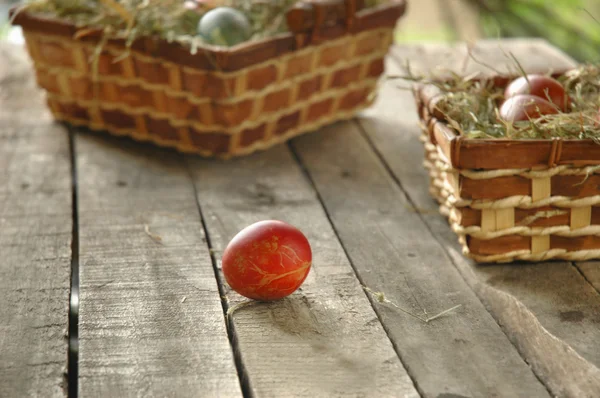 用篮子在旧木桌上的红色复活节彩蛋。 — 图库照片