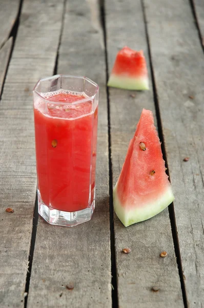 Watermelon juice and slices on gray wooden background — Stock Photo, Image