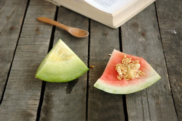 Watermelon and melon leftovers with wooden spoon and book — Stock Photo, Image