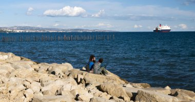 Young sitting on stony pier clipart