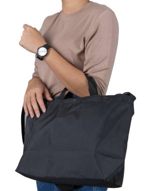 İzole edilmiş yakın çekim stüdyo çekimi. Moda modasına uygun, kadın kolunda asılı bir çanta. Uzun kollu gömlek ve beyaz arka planda duran kol saati ile kot pantolon giyiyor..