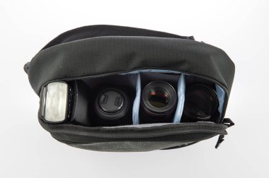 Küçük, siyah ve gri profesyonel fotoğrafçının kapalı çekim stüdyosu şok geçirmez, su geçirmez kumaş, fermuar çanta beyaz arka plandaki yumuşak bölmede flaş ve lens içeriyor..