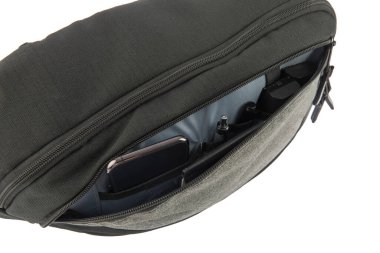 Profesyonel fotoğrafçı siyah kamera çantasının ön fermuar cebinde izole edilmiş bir fotoğraf stüdyosu. Cüzdan, akıllı telefon kalem kalem bataryası ve beyaz arka fonun önünde sutürlü..