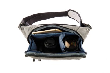 Küçük fotoğrafçı yakın çekim stüdyosu modern moda gri şok geçirmez bel çantası yumuşak bel çantası dijital DSR kamera len ve akıllı telefonu beyaz arka planda taşıyor..