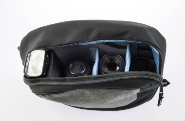 Küçük, siyah ve gri profesyonel fotoğrafçının kapalı çekim stüdyosu şok geçirmez, su geçirmez kumaş, fermuar çanta beyaz arka plandaki yumuşak bölmede flaş ve lens içeriyor..