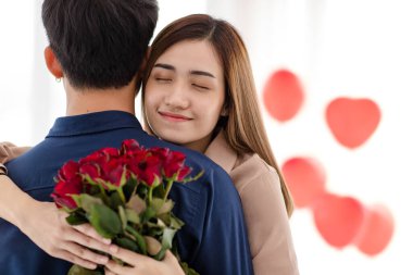 Bir buket çiçekli Asyalı kadın Sevgililer Günü kutlamasında adama sarılıyor ve gözlerini kapıyor. Genç aşıkların aşk ve ilişkisi.