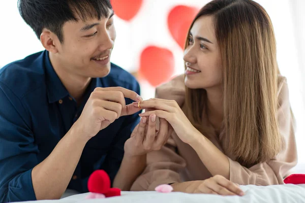 聖バレンタインの日に喜んでくれる女性の指に婚約指輪をはめながら笑顔の幸せなアジア人男性 十代の恋人の概念の公開愛と関係 — ストック写真