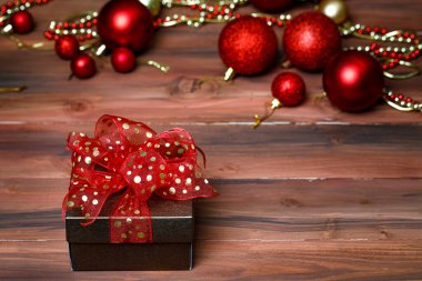 Hediyelik hediye kutusunun yakın plan görüntüsü. Altın kurdele yayı ile sarılmış. Öndeki parlak, parlak ahşap masaya yerleştirilmiş..