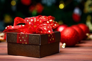 Hediyelik hediye kutusunun yakın plan görüntüsü. Altın kurdele yayı ile sarılmış. Öndeki parlak, parlak ahşap masaya yerleştirilmiş..