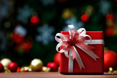 Hediyelik hediye kutusunun yakın plan resmi. Kurdele yayı ile sarılmış. Eski, koyu ahşap masa üzerine yerleştirilmiş..