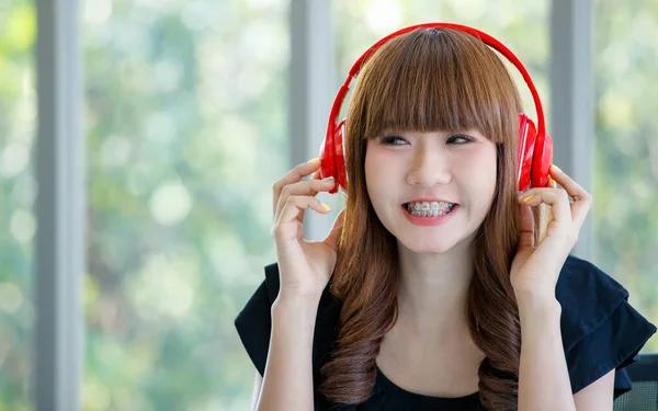 잘생긴 아시아 여자붉은 헤드폰으로 음악을 배경의 나무와 행복하고 즐거운 모습으로 — 스톡 사진