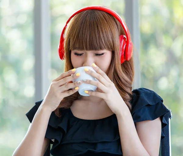 잘생긴 아시아 여자붉은 헤드폰으로 음악을 커피를 마시는 음악을 — 스톡 사진