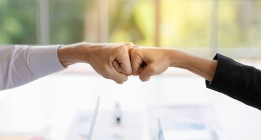 Tanımlanamayan iş adamı ve iş kadını yumruklarının son anlaşma başarısından sonra yakın plan çekimleri. Şirket toplantı odasında proje onayı anlaşması satılıyor.