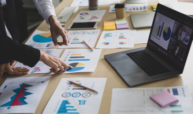 Tanımlanamayan işadamı ve işkadını şirket analizlerine bakarak, istatistik grafik çizelgesine göre masadaki evrakları rapor ediyorlar. Dizüstü bilgisayardaki meslektaşlarımla telekonferans.
