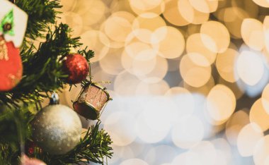Kırmızı parlak Noel arifesi süslemeleri yakın çekim yeşil Xmas çam ağacı dalında asılı küre topları ve diğer süslemeli şeyler ön bulanık ışık arka plan bokeh.