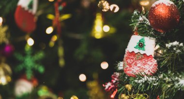 Kırmızı ve beyaz sahte kar süslemeli çorap yakın çekim yeşil çam ağacının dalında asılı Xmas arifesinde geleneksel festival gecesi etkinliğinde bulanık arka planda.