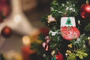 Kırmızı ve beyaz sahte kar süslemeli çorap yakın çekim yeşil çam ağacının dalında asılı Xmas arifesinde geleneksel festival gecesi etkinliğinde bulanık arka planda.