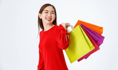 Sevindim Asyalı 40 'lı yaşlarda güzel bir bayan renkli alışveriş torbaları gösteriyor ve mutlu ve neşeli bir müşteriyle kameraya bakıyor stüdyoda beyaz arka planda