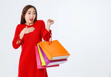 Renkli kağıt alışveriş torbaları olan Asyalı harika bir bayan müşteri ya da alıcı beyaz arka planda terfi için heyecanlı ve şaşırmış duruyor ve şaşkınlıkla başka tarafa bakıyor.