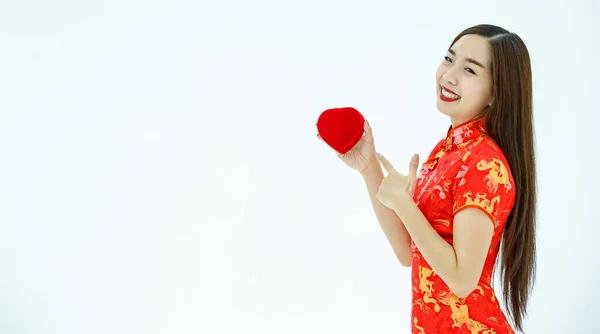 喜びに満ちたアジアの女性のサイドビューで赤いドレスは箱を指しています — ストック写真