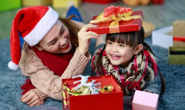 Çekici Asyalı anne-kız kışlık kıyafetler giyiyorlar ve Noel Baba 'nın şapkasıyla Noel' i neşeyle kutluyorlar. Süslü Noel ağacı arka planı. Aile Noel partisi kavramı.