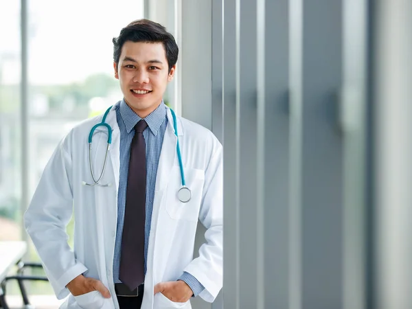 Üniformalı Neşeli Genç Yakışıklı Asyalı Erkek Doktor Steteskopla Klinikte Elleri — Stok fotoğraf