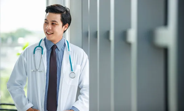 Veselý Mladý Roztomilý Asijský Lékař Uniformě Stetoskopem Stojící Rukama Kapsách — Stock fotografie