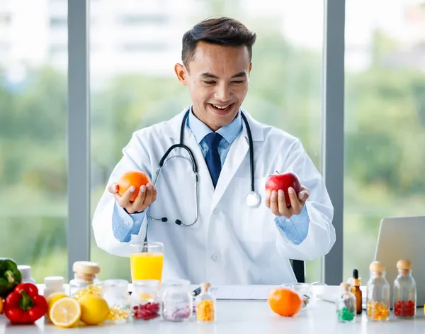 Alegre Nutricionista Masculino Asiático Uniforme Blanco Sentado Mesa Con Una — Foto de Stock