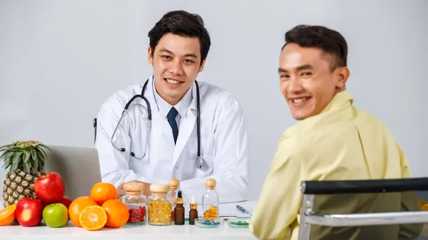 Macho Asiático Alegre Nutricionista Paciente Sentado Mesa Com Frutas Suplementos — Fotografia de Stock