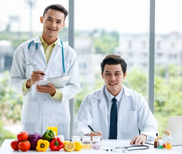 Tıp Üniformalı Asyalı Erkek Meslektaşlar Modern Klinikte Çalışırken Meyvelerle Birlikte — Stok fotoğraf