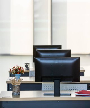 Modern iç mekan, ofis ya da işyerinin arka plan fotoğrafı ve ahşap masalar üzerinde sıralı bilgisayarlar. Teknoloji ve İş Konsepti