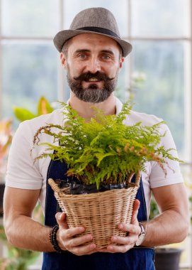 Şapka ve önlük takan güzel sakallı bir adam elinde mutlu ve gururlu küçük bir ağaç kabuğu tutuyor..