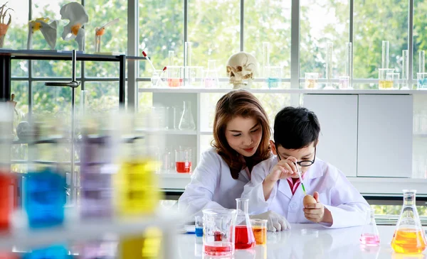 아시아의한 남학생 실험실에서 수업을 교사의 도움을 실험을 하면서 액체를 혼합하는 — 스톡 사진