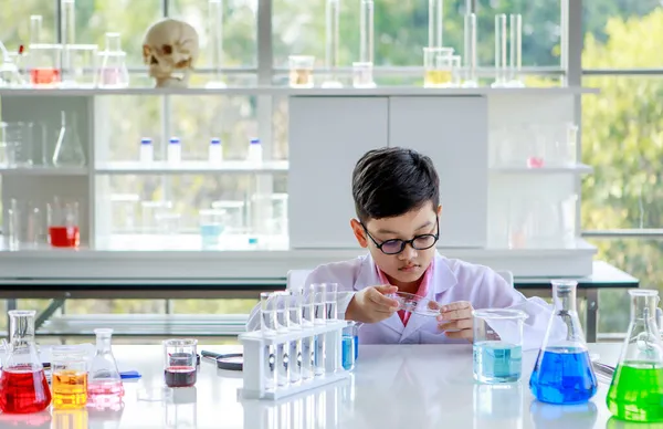 실험실에서 화학을 공부하면서 실험실 코트와 안경으로 표본을 조사하는 아시아 학생에게 — 스톡 사진