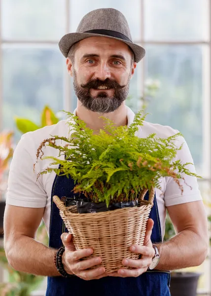 Şapka ve önlük takan güzel sakallı bir adam elinde mutlu ve gururlu küçük bir ağaç kabuğu tutuyor..