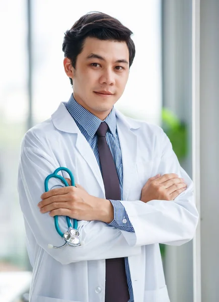 思慮深い若いアジアの男性の肖像医学室で聴診器で立って離れて見て医師または医師 — ストック写真