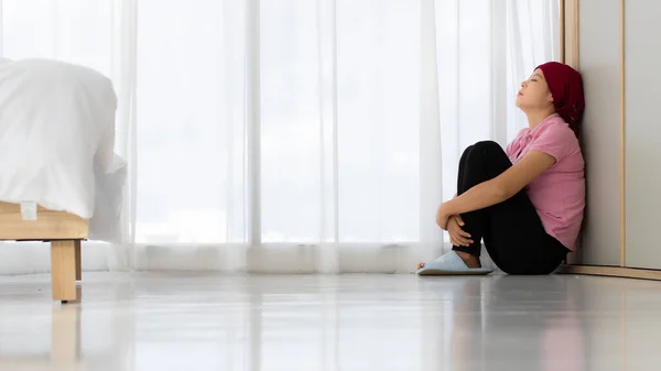 不幸的是 患有乳腺癌的亚洲女人孤独地坐在地板上 靠着墙 抱着膝盖坐在靠近窗帘的卧室角落 绝望极了 对药物治疗失败感到气馁 — 图库照片