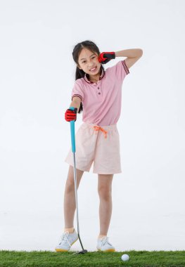 Spor formalı mutlu Asyalı golfçünün izole edilmiş bir fotoğrafı yeşil çimlerin üzerinde duruyor golf sopası sürücüsünü ellerinde neşeli bir şekilde beyaz arka plan önünde gülüyor gibi yapıyor..
