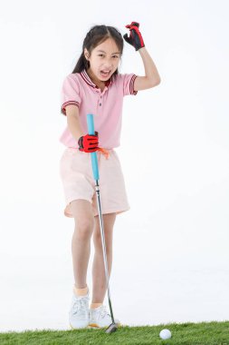 Spor formalı mutlu Asyalı golfçünün izole edilmiş bir fotoğrafı yeşil çimlerin üzerinde duruyor golf sopası sürücüsünü ellerinde neşeli bir şekilde beyaz arka plan önünde gülüyor gibi yapıyor..