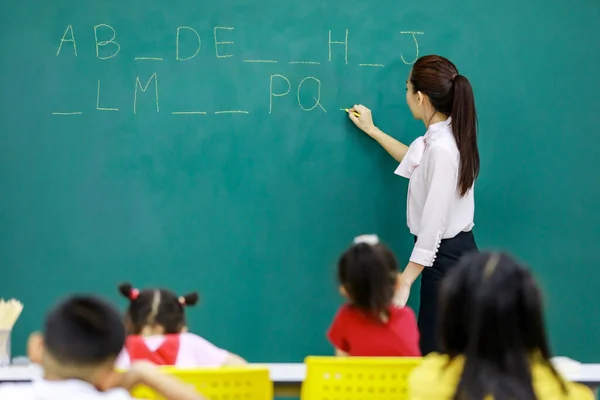 아시아인 여학생의 초등학생들을 칠판에 문자를 강사가서 모습의 초등학생의 초상화 — 스톡 사진