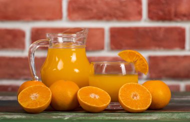 Temiz kavanozda taze portakal suyu ve renkli ahşap masada taze portakalla süsleme. Sağlıklı beslenme için stüdyo resmi konsepti. Stüdyo resmi.