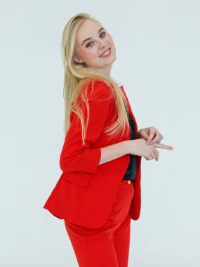 Kırmızı elbiseli hoş sarışın kadının kapalı alanda çekilmiş portresi beyaz arka planda izole edilmiş neşeli ve olumlu duygularla reklam jestinde kameraya poz veriyor..