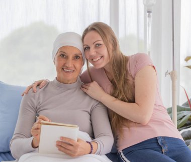 Kadın ve kadın kanser hastaları, mutlu bir şekilde deftere yazı ve yazı yazmaktan hoşlanırlar. Destek ve teşvik için fikir.