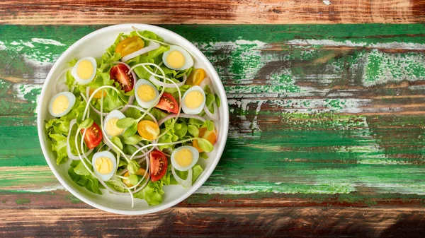 レタスの大きな白いボウル カラフルな木製のテーブルの上にゴマドレッシングと混合ゆで卵とサラダを発芽 玉ねぎとトマト 健康の概念 — ストック写真
