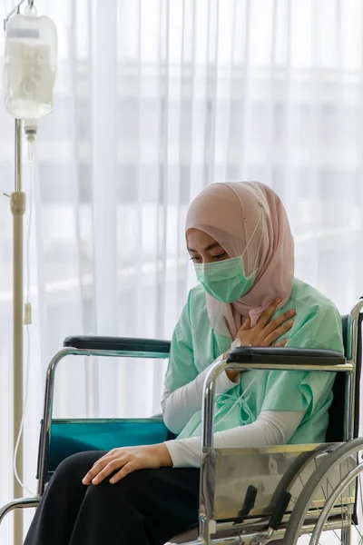 病気の肖像患者のガウンを着て 病院で生理食塩水の袋を添付して車椅子に座っているイスラム教徒の顔のマスク Covid 19パンデミックの概念 — ストック写真